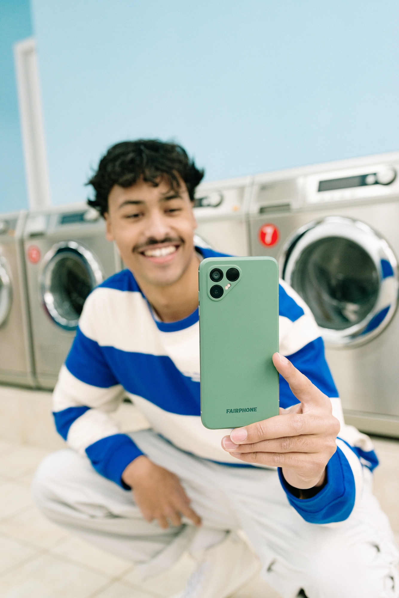 En mand tager et billede med en Fairphone 4 i et vaskeri