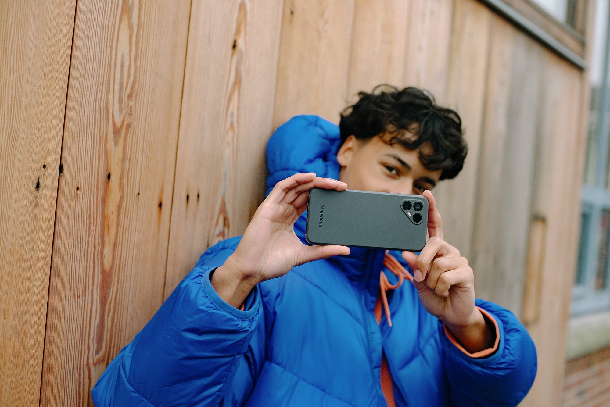 Ung mand holder en Fairphone 4 op foran ansigtet og tager et billede