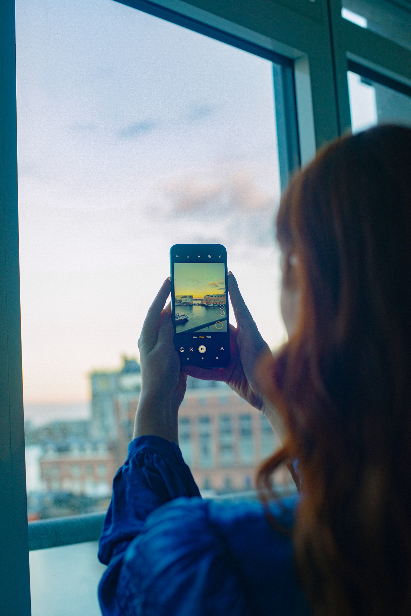 Kvinde tager et billede ud ad vinduet med Fairphone 4