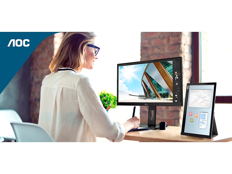 Kvinde sidder ved et skrivebord og arbejder på en AOC-skærm