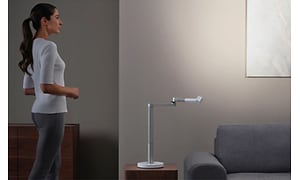 Kvinde, der står ved siden af Dyson Lightcycle Morph bordlampe