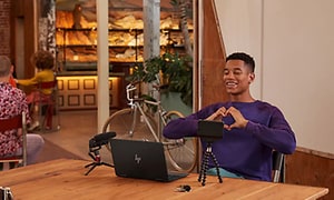 Mand foretager video opkald med en HP Envy - han smiler og laver hjerte-tegn med sine hænder
