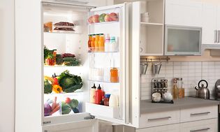 Integreret køleskab med åben dør i hvidt køkken