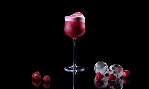 En rød drink med bær og isterninger