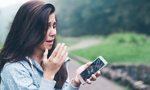 Kvinde ser forskrækket på knust smartphone
