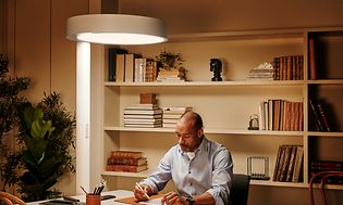Mand arbejder ved et bord med BrainLit Alven-lampe som oplyser arbejdsrummet