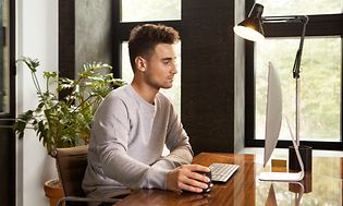 Mand arbejder i et kontor foran en computer og med Contour Unimouse