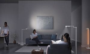Den samme kvinde står og sidder rundt i en stue med Dyson-belysning