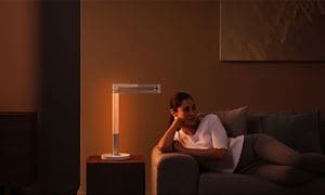 Kvinde liggende på en sofa ved siden af en Dyson-lampe