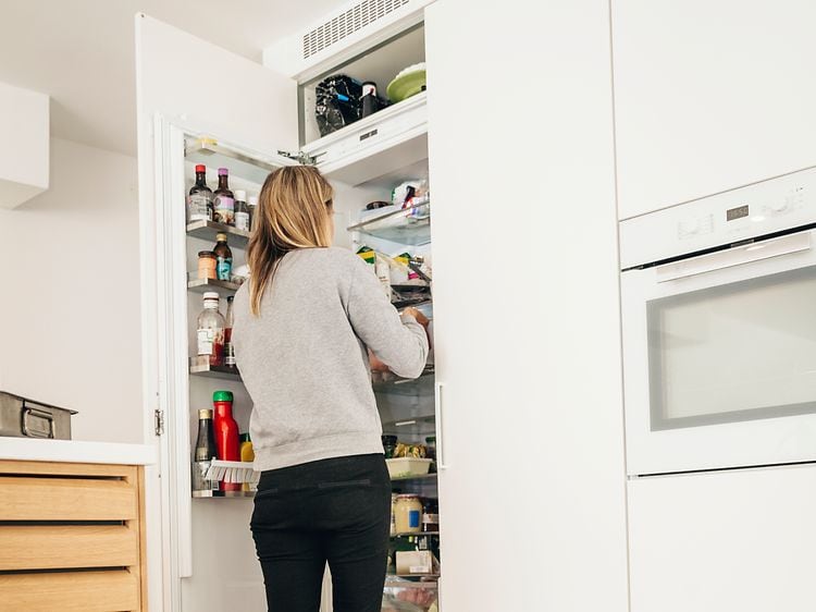 Kvinde og baby kigger ind i køleskab for at finde mad