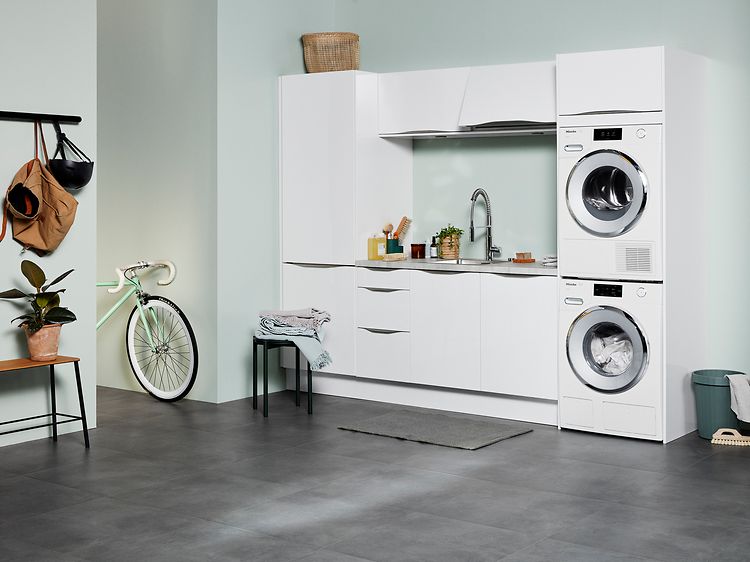 Hvid EPOQ Gloss White vaskerum i en åben bryggersløsning med en vaskemaskine og en tørretumbler