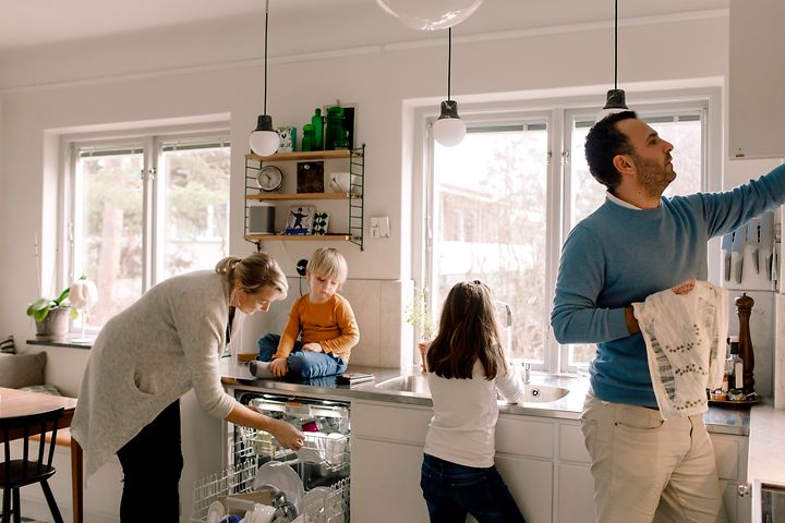 MDA-Dishwashers- Familie i et køkken, der tager et rent fad frem