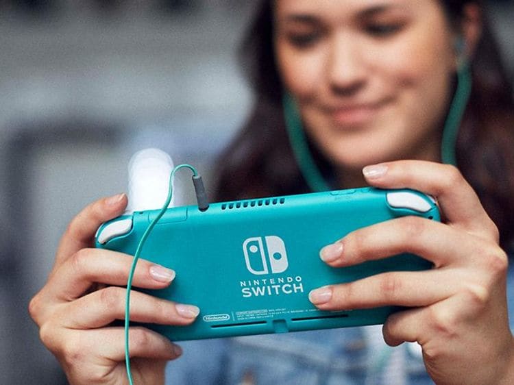 Smilende kvinde spiller turkis Nintendo Switch Lite