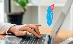 En hånd over en bærbar computer og et e-mail-symbol