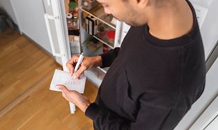 MDA-Køleskabe-Mand tager notater foran et åbent køleskab