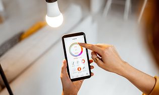 En kvinde justerer den smarte belysning på smartphone-appen