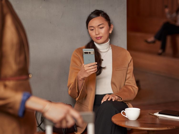 Kvinde sidder ved et café-bord mens hun kigger på sin Pixel telefon