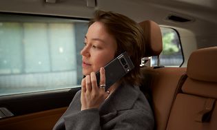 Kvinde sidder på bagsædet af en bil og snakker i hendes Pixel 7 Pro