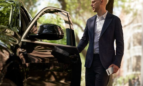 Man standing next to a car holding his Google Pixel 7 Pro in his hand