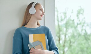 Kvinde med Sony hovedtelefoner med notesbøger i hånden