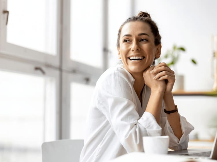 En smilende kvinde foran sin bærbare computer