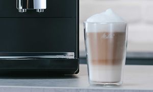 Et glas cafe latte og en Melitta kaffemaskine