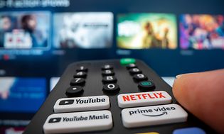 Fjernbetjening med Netflix -, Youtube- og Amazonknapper, peget mod et tv 