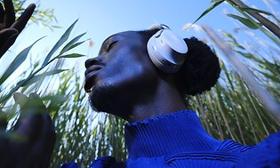 Bose QuietComfort Ultra Wireless støjreducerende hovedtelefoner på hovedet af ung mand, der går rundt på en mark