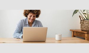 Kvinde sidder foran en computer og smiler