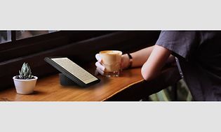 Person sidder med en kop kaffe og en Kobo e-bogslæser på en café