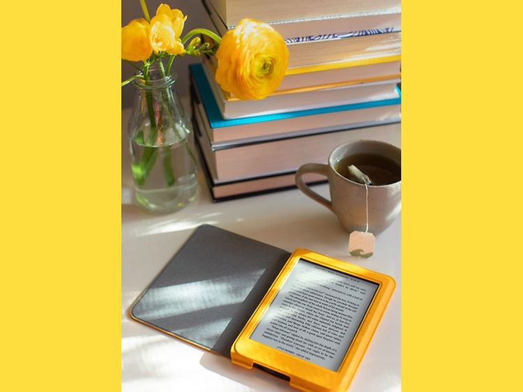 Kobo e-bogslæser på et bord og en kop kaffe og en blomsterbuket