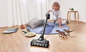 Barn rengør gulvet rundt om legetøj med en ledningsfri Bosch støvsuger