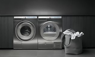 Professionel vaskemaskine og tørretumbler i rustfrit stål placeret ved siden af ​​hinanden