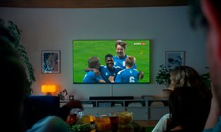 TV i en stue, som viser fodboldspillere, der fejrer et mål