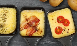 Tre raclette-pander med ost og topping