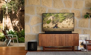 Sort Sonos Arc under et TV og Sonos Sub ved siden af TV-bænken i en stue