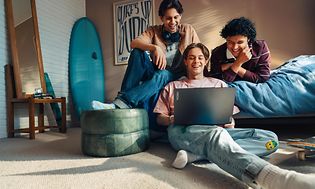 Tre unge mænd kigger på en Lenovo-laptop