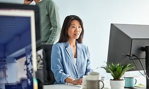 Kvinde, der sidder foran en arbejdscomputer på et kontor