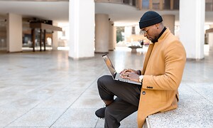 Mand sidder på trappe med Asus Vivobook S 15 laptop