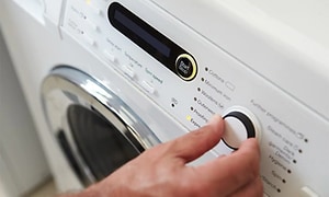 En hånd der tænder vaskemaskinen