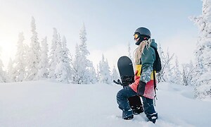 kvinde gør i dyb sne med sit snowboard i hånden